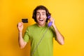 Photo of funny excited man hold telephone talk show debit card wear green t-shirt isolated yellow color background