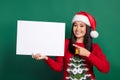 Photo of funny excited vietnamese lady wear red santa claus hat finger direct empty paper blank useful information