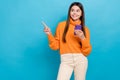 Photo of funny friendly interested girl wear knit turtleneck directing look empty space hold phone isolated on blue