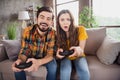 Photo of funny gamer couple hold gamepad play videogame enjoy weekend wear casual clothes sit couch home indoors