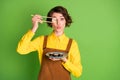 Photo of funny girl hold chopsticks plate sushi hide eye with roll pout lips wear yellow shirt overall isolated green Royalty Free Stock Photo