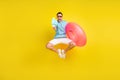 Photo of funny impressed man wear blue t-shirt dark glasses holding water circle shooting water gun isolated yellow