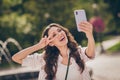 Photo of funny laughing long brown curly hair young woman doing selfie show v-sign enjoy weekend in park wear striped Royalty Free Stock Photo