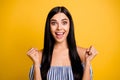 Photo of funny lucky young lady wear striped dress rising two fists isolated yellow color background