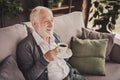 Photo of funny pensioner wear grey cardigan sitting couch having rest drinking coffee indoors house flat