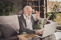 Photo of funny pensioner wear grey cardigan sitting looking modern gadget have video call indoors house flat