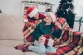 Photo of funny positive children exchange surprise presents wear x-mas hat jumper in decorated home indoors