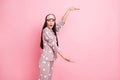 Photo of funny shocked young woman dotted sleepwear mask measuring arms big empty space isolated pink color background