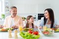 Photo of funny smiling married couple small daughter laughing eating fresh dinner indoors home kitchen Royalty Free Stock Photo