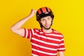 Photo of funny unsure young guy dressed red t-shirt hands arm fist safety hat isolated yellow color background