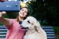Photo of girl on bench doing selfie with retriever Royalty Free Stock Photo