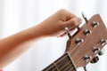 Photo of girl`s hand tuning acoustic guitar, close-up