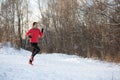 Photo of girl in sports uniform on morning run in winter forest Royalty Free Stock Photo