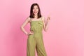 Photo of girlish adorable gorgeous woman wear khaki overall impressed pointing empty space hand on waist isolated on