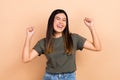 Photo of glad asian girl raise fists rejoicing achievement results eyes closed wear stylish clothes isolated beige color