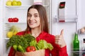 Photo of glad female shows ok sign and demonstrates approval, holds vegetables, comes from grocer`s shop, being in good mood has n