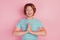 Photo of glad hopeful man hold hands together ask help wear casual blue striped t-shirt on pink background