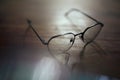 Photo of glasses on wooden table with bokeh and blurred reflection. Shallow depth of field. Bad eyesight concept image with copy