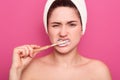 Photo of good looking woman brushing her teeth, frowning face in displeasure, dissatisfied with new toothbrush ortoothpaste,
