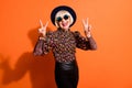 Photo of good mood happy smiling positive old woman show v-sign wear sunglasses black headwear isolated on orange color