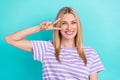 Photo of good mood optimistic nice woman with straight hairstyle wear striped t-shirt showing v-sign isolated on blue Royalty Free Stock Photo