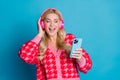 Photo of good mood woman wear knit cardigan touch headphones look at smartphone listen stereo sound isolated on blue Royalty Free Stock Photo