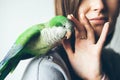 Photo of a green Quaker parrot sitting on woman`s hand. Royalty Free Stock Photo
