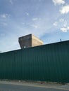 Photo of green zinc fence on asphalt road and partially concrete pillar in the morning Royalty Free Stock Photo