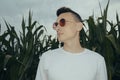 Photo of a guy in fashionable sunglasses. A man in a corn field with leaves. Evening photo with flash