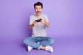 Photo of guy hold joystick open mouth play game have fun wear white t-shirt jeans footwear isolated violet background