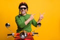 Photo of guy ride bike indicate forefingers empty space wear helmet eyeglasses green sweater isolated yellow color Royalty Free Stock Photo