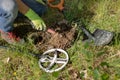 photo a hand in a glove using a pinpointer looks for a treasure in the dug-out earth, but found rubbish. in the foregroun Royalty Free Stock Photo