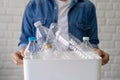 Photo of hand holding white recycling bin with many plastic bottles