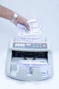 Photo of hand putting Indian currency in cash counting machine