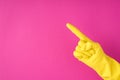 Photo of hand in yellow glove making pointing symbol with forefinger on isolated pink background with copyspace