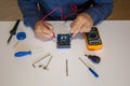 Photo of the hands of a man using a tester to repair an electrical board of a battery pack. Homemade repair work