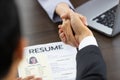 Photo of handshake above a resume of woman applicant for congratulations on getting a job. Selective focus on handshaking. Concept Royalty Free Stock Photo