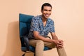 Photo of handsome attractive man wear print shirt sitting office armchair smiling beige color background