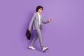 Photo of handsome confident pupil guy walk move carry case wear grey suit footwear isolated purple color background