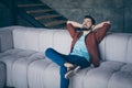 Photo of handsome guy in high spirits holding hands behind head sitting comfortable big couch sleeping relaxing saturday