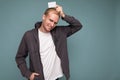 Photo of handsome happy smiling blonde man wearing grey sweater and white t-shirt isolated over blue background wall Royalty Free Stock Photo