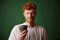 Photo of handsome redhead bearded young man, holding potted plan