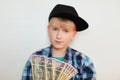 A photo of handsome stylish liitle rich child dressed in black cap and modern shirt holding dollars in his hands. Young businessma Royalty Free Stock Photo