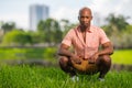 Photo handsome young African American man squatting on grass in the park. Deadpan expression staring deep into the camera