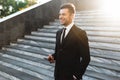 Handsome young businessman walking outdoors at the street using mobile phone Royalty Free Stock Photo