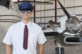 Portrait of handsome young pilot standing in front of airplane