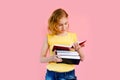 Photo of happy charming blonde girl posing with exercise books and smiling isolated over pink background Royalty Free Stock Photo