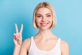 Photo of happy cheerful nice young woman hold hand show v-sign smile isolated pastel blue color background Royalty Free Stock Photo