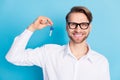 Photo of happy cheerful young man realtor hold keys new house relocation isolated on blue color background