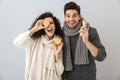 Photo of happy couple man and woman wearing scarfs holding lemons and ginger, isolated over gray background